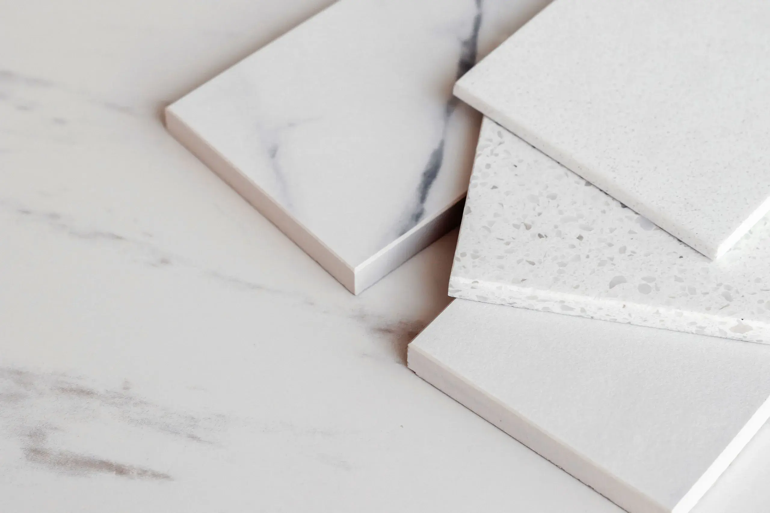 A picture of four white countertop samples spread out on a marble countertop.