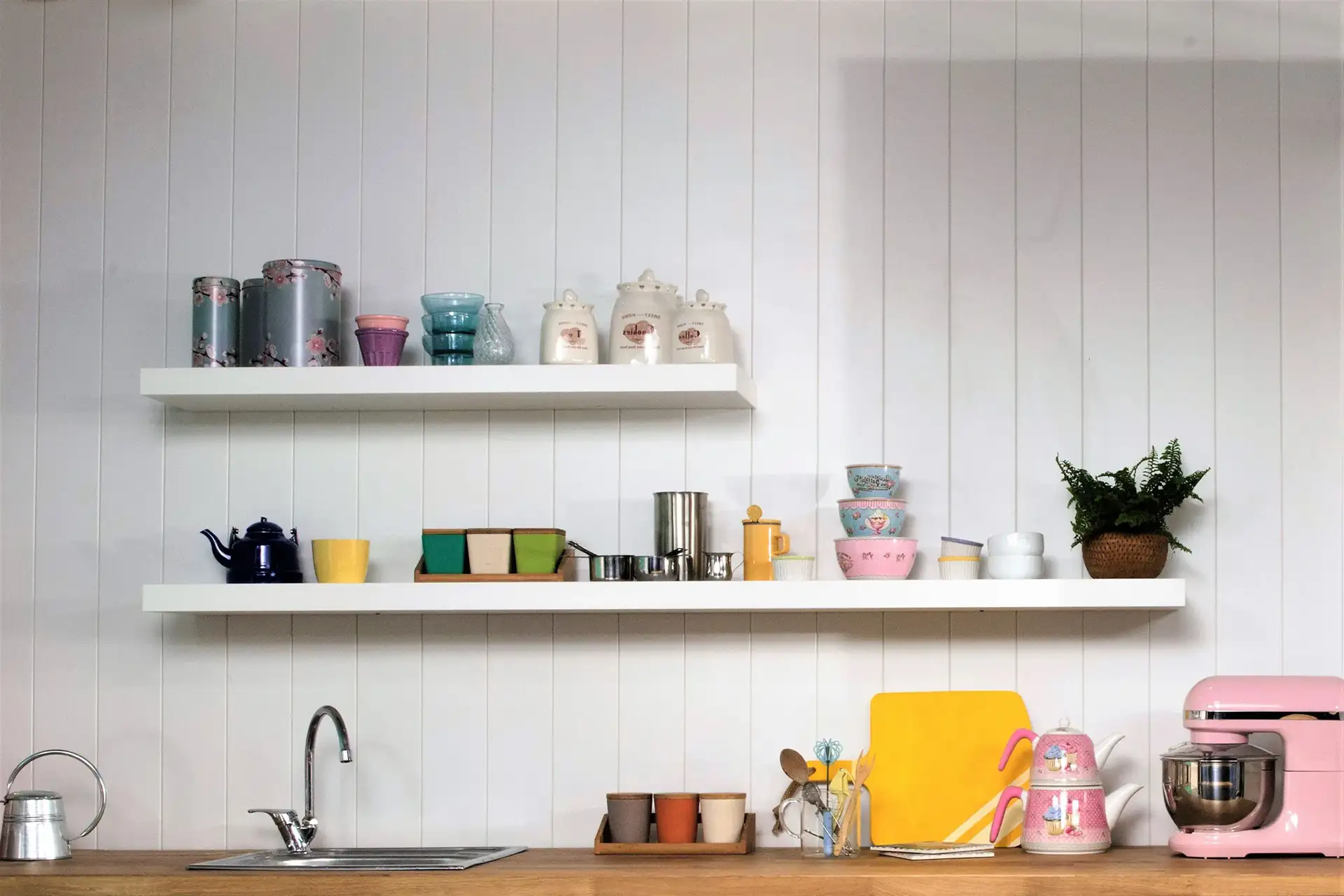A picture of a kitchen with two white floating shelves with decorative trinkets accenting them.