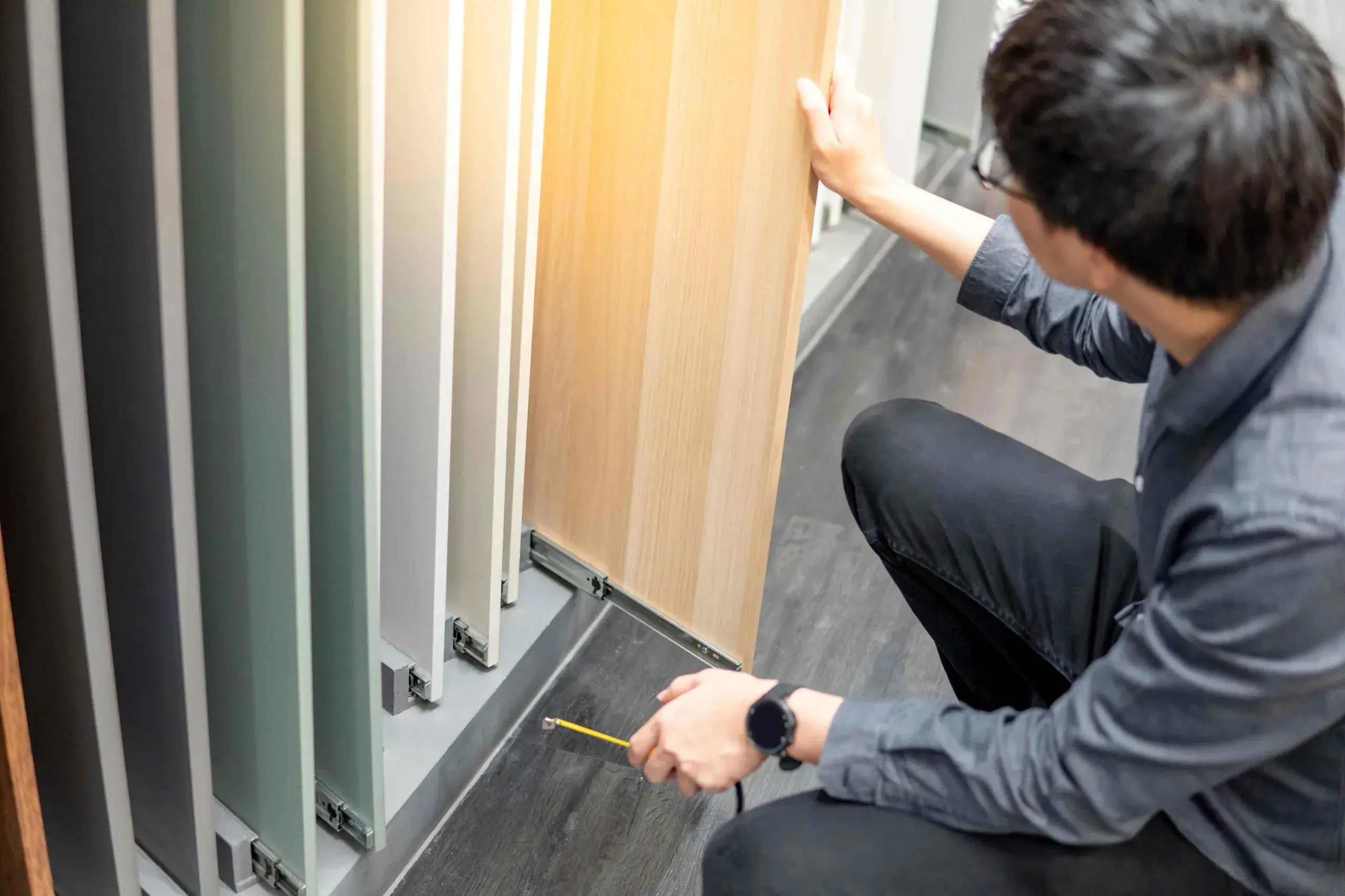 An image of the top of a person's head as they pull a cabinet door sample out of a rack. A av