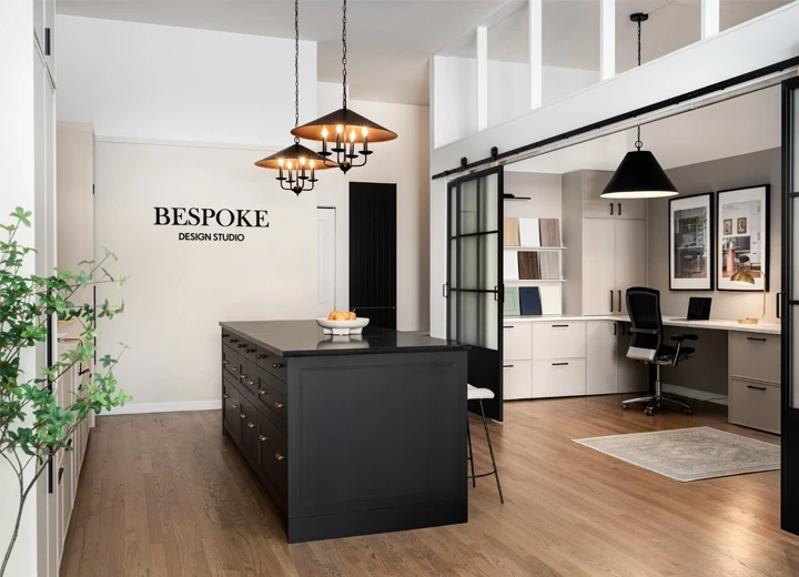 A showroom space with cabinet door samples on the wall, a black kitchen island, and design studio space.