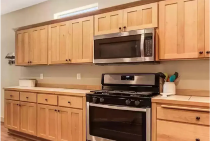 An image of a kitchen with dated double panelled shaker style golden oak cabinet doors.