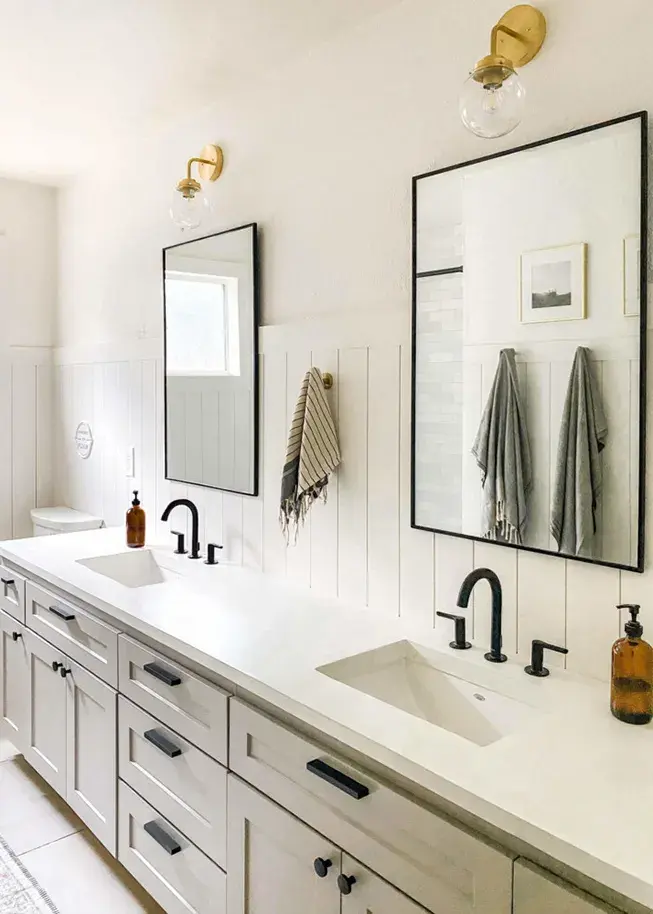 A bathroom vanity with Shallow Shaker taupe cabinet doors, matte black hardware, faucet, and concerete countertops, with black framed mirrors and grey towels.