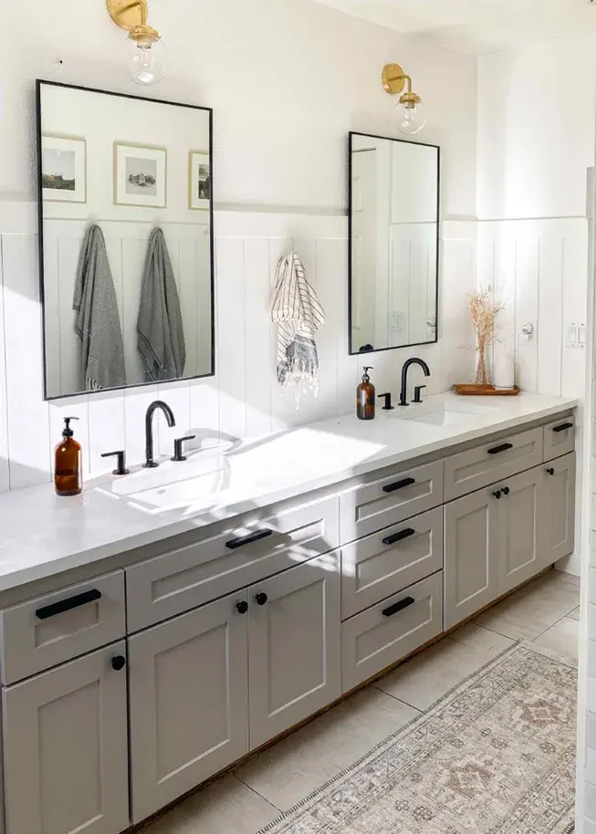 A bathroom vanity with Shallow Shaker taupe cabinet doors, matte black hardware, faucet, and concerete countertops, with black framed mirrors and grey towels.