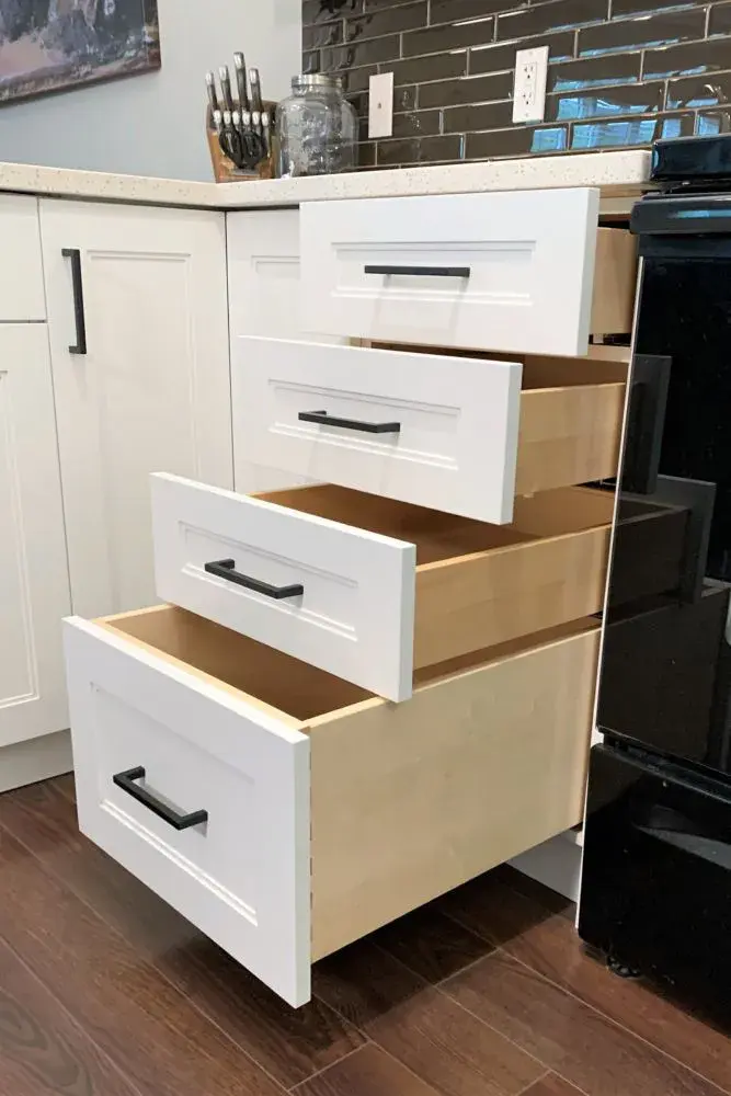 An image of a stack of dovetail drawers showing the dovetail joinery, paired with white stepped shaker drawer fronts.
