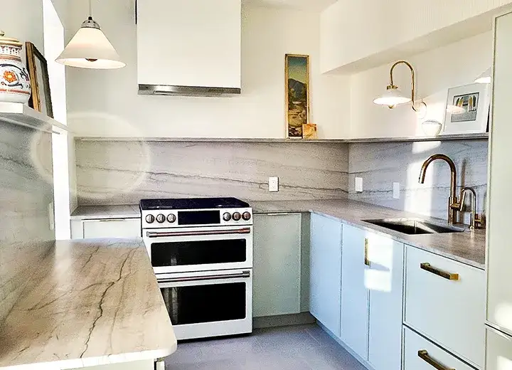 A photo of an IKEA kitchen with white Skinny Shaker doors, marble countertops, a white range, and a plaster range hood.