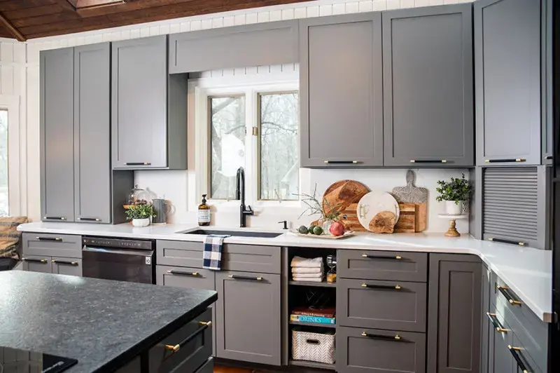 An image of Kortney Wilson's lake house kitchen with gray cabinetry, white quartz countertops, and black hardware.