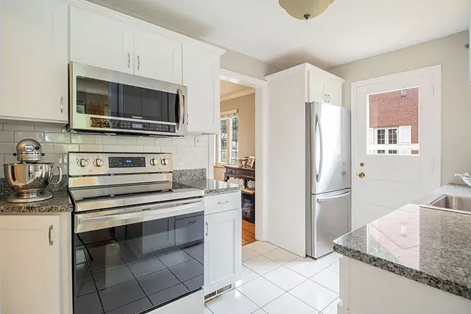 An image of a kitchen with white shaker cabinets and stainless steel appliances.