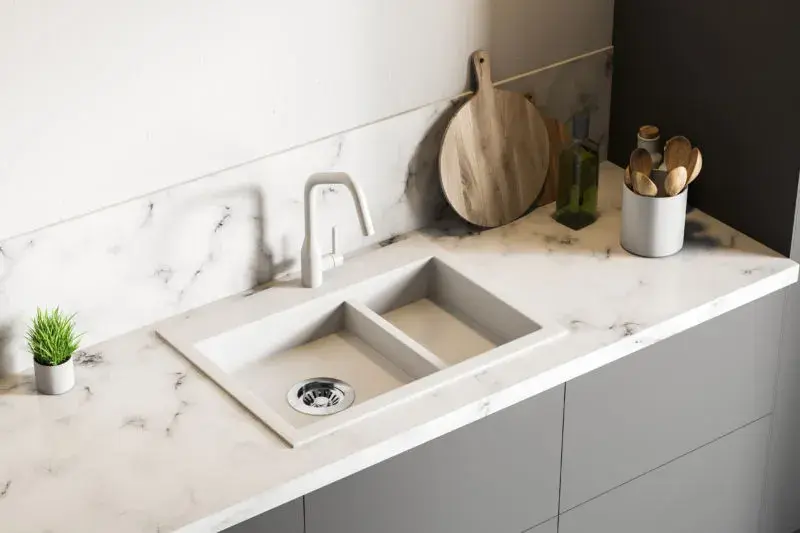 An image of a marble countertop with grey veining, a white sink, and white faucet.