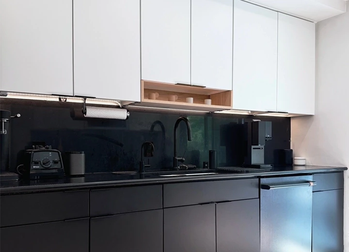 A showroom space with cabinet door samples on the wall, a black kitchen island, and design studio space.