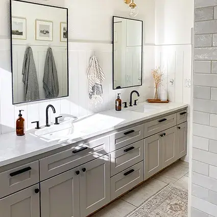 An image of a bathroom vanity with taupe shallow shaker cabinet doors, concret countertops, and matte black hardware and faucets.