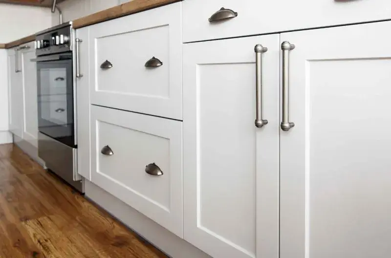 An image of base cabinet doors in a kitchen made from MDF that are shaker style, painted white, with brushed nickel hardware.