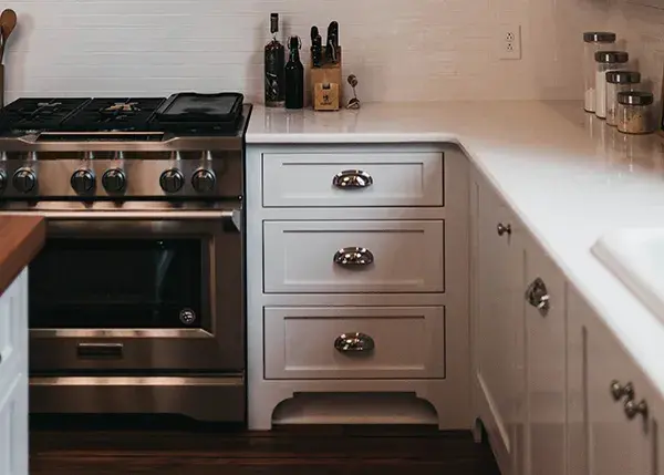 An image of a a bank of kitchen drawers with silver cup pulls beside a slide in range.